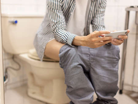 young man wearing casual clothes at home, lying in bed using laptop to surf the Internet, reading/watching movies, chatting on the phoneの写真素材