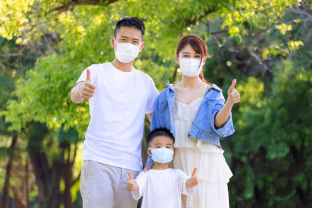 Happy family wearing medical masks to protection and showing thumbs upの写真素材
