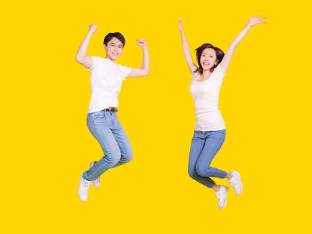 Young couple smiling at camera while woman putting her head on male shoulder .Isolated over yellow background.の写真素材