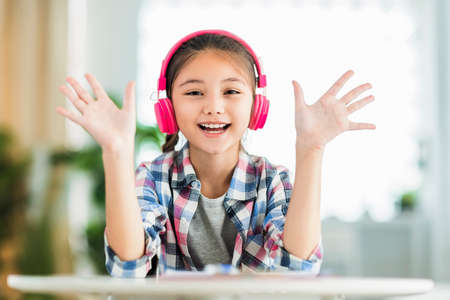 Happy student girl in headphones, saying hi, look at camera.