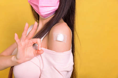 woman wearing protective mask  with showing her arm with ok gesture after getting vaccine.の写真素材