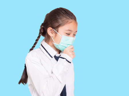 Girl in a medical mask coughing.Isolated on blue background.の写真素材