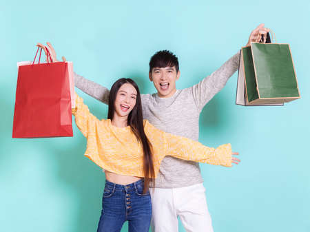 Excited young couple holding shopping bags.Isolated on blue background.の写真素材