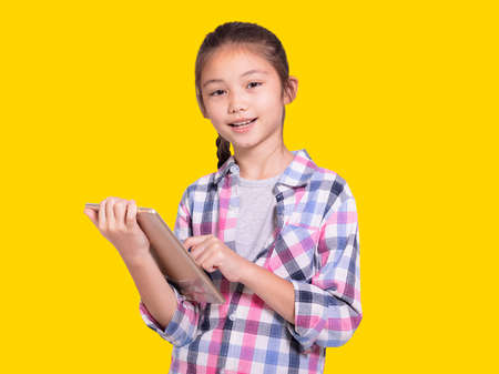 Happy student girl using tablet.Isolated on yellow background.の写真素材
