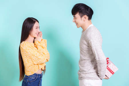 Young man giving a surprise gift to woman.Isolated on blue background.の写真素材