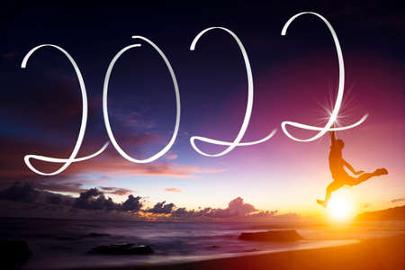 Man drawing 2022 by flashlight on the beach at sunrise.Happy new year 2022 conceptsの写真素材