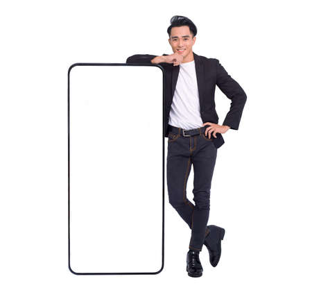 Happy young man standing and Leaning big Smartphone With Blank White Screenの写真素材