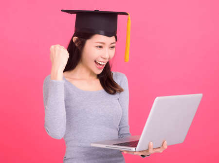Happy Asian girl college student in Graduation cap and holding laptop