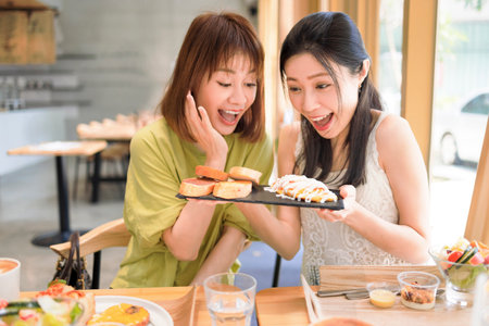 Happy girlfriends having lunch together at restaurantの写真素材