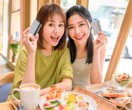 Happy Beautiful young women showing the credit card in restaurant