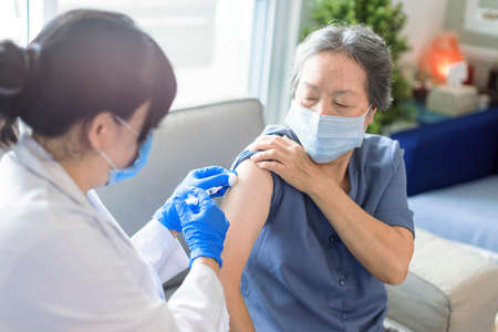 Senior woman receiving vaccine. Medical doctor vaccinating an elderly patient against flu, covid-19, pneumonia or coronavirus.の写真素材