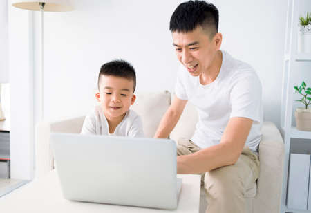 Child educate online. Father help son with home work. Boy in video conference with teacher on laptop at home.の写真素材