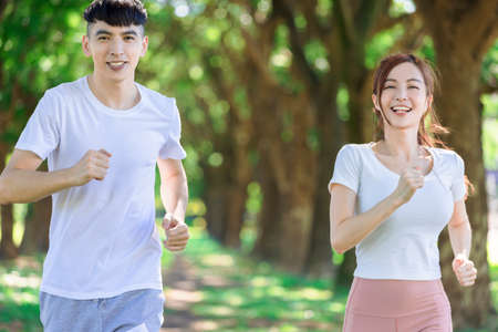 young couple jogging together in the park on sunny dayの写真素材
