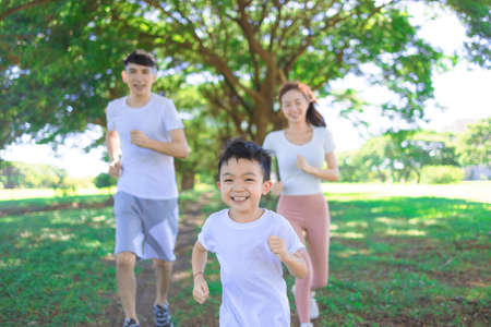 Happy little boy Jogging with parents in the city parkの写真素材