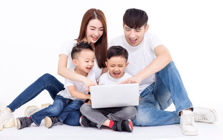 Happy Asian family sitting on white floor and using the laptop