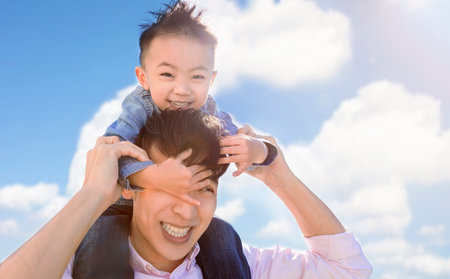 Happy father carrying young boy on back and playing at the parkの写真素材