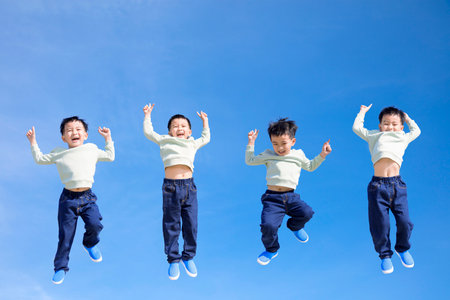 Happy kid jumping and gesturing against blue skyの写真素材