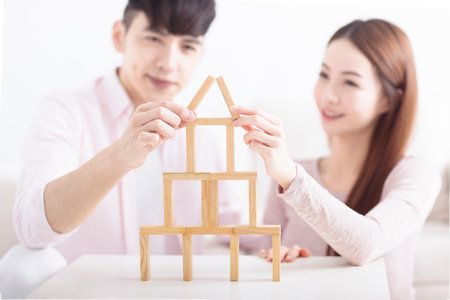 Happy young couple building house by with wooden bricks for home conceptの写真素材