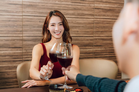 Young happy couple celebrating and toasting with wine glasses in restaurant.の写真素材