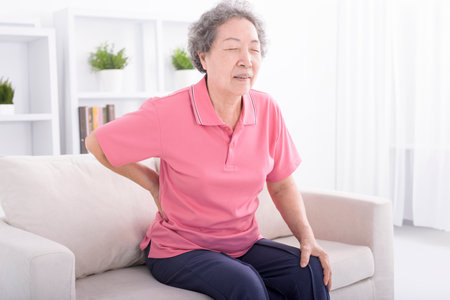 Senior woman suffering from back pain at homeの写真素材