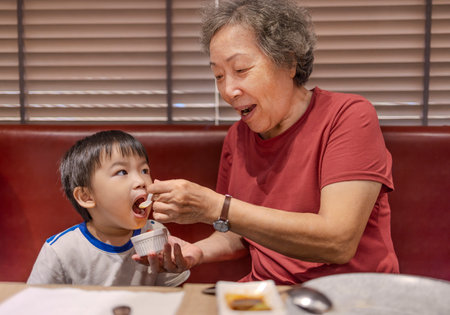 Happy grandmother feeds her grandson in restaurant