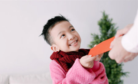 happy asian little boy receiving red envelope and celebrating chinese new yearの写真素材