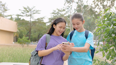 Happy Asian student girls walking and using smart phone in schoolの写真素材