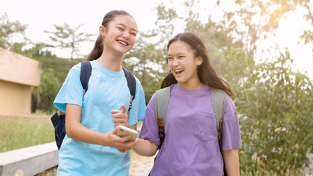 Happy Asian student girls walking and using smart phone in schoolの写真素材