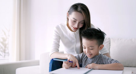 Young mother checking homework helping child with study at homeの写真素材