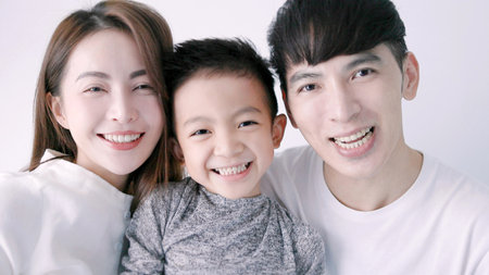 Happy family and child hugging and looking at cameraの写真素材