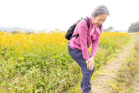 Senior woman with knee pain while hiking in the parkの写真素材