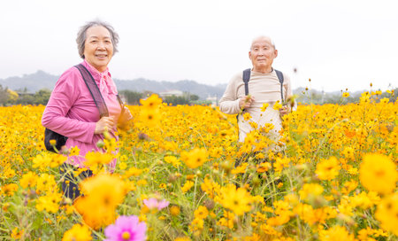 Happy senior couple hiking on trail by flowers plants at springの写真素材