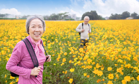 Happy senior couple hiking on trail by flowers plantsの写真素材