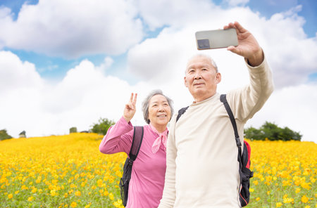 Happy senior couple taking selfie by smart phone at springtime travelの写真素材