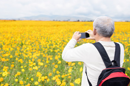 Senior man taking photos with his mobile phoneの写真素材