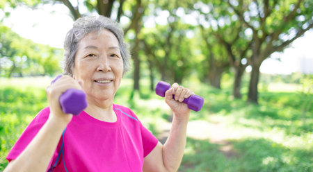Happy Asian senior woman lifting dumbbellの写真素材
