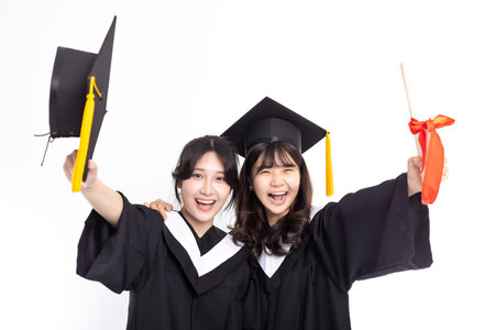 Excited Teenage girls wearing graduation gown and showing diploma