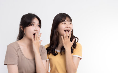 Surprised two cheerful young women standing togetherの写真素材