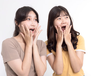 Surprised two cheerful asian girls standing togetherの写真素材