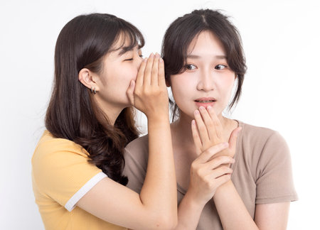 Portrait of two beautiful gossiping girlsの写真素材