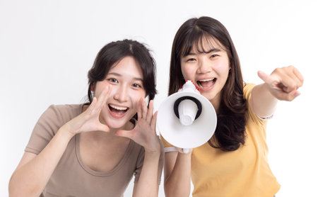 Happy Girls shouting with friend by megaphoneの写真素材