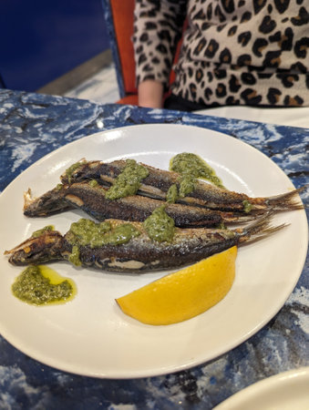 Fried Sardines with lemon and Salsa Verde on a white plateの写真素材