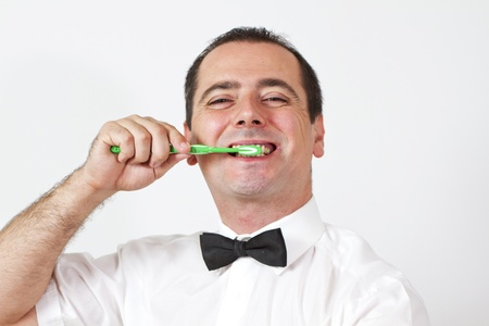 Guy with bow tie is brushing teeth and have awkward smileの写真素材