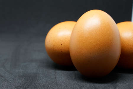 fresh chicken eggs laid out on a black background.