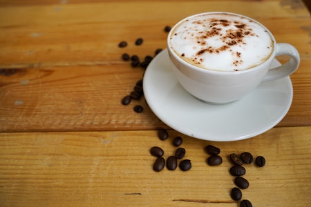 Hot cappuccino in white cup with wooden background,coffee is a popular drink all over the world.の写真素材