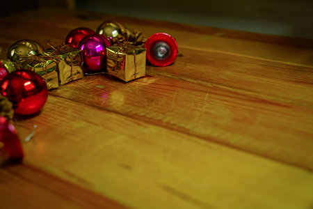 New Year and Christmas gift themed decorations on wooden background, consisting of a golden gift box.  shiny colored balls  Dried pine cones and small bells  free space for designの写真素材