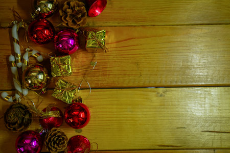 New Year and Christmas gift themed decorations on wooden background, consisting of a golden gift box.  shiny colored balls  Dried pine cones and small bells  free space for designの写真素材