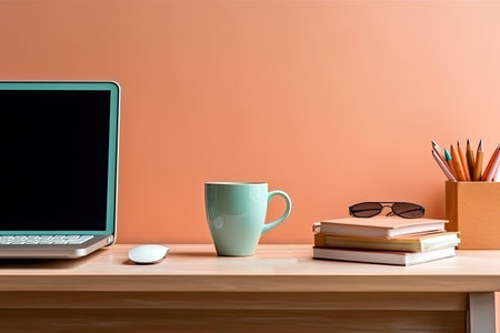 Laptop, books and coffee cup on wooden table near orange wallの素材