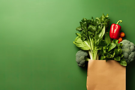 Paper bag with fresh vegetables on green background. Healthy food concept.の素材