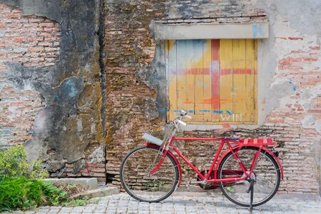 Old red bicycle on old city crack wall background.の写真素材